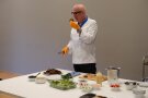 Mann in Kochkleidung riecht an einem Bratling.