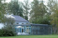 Gebäude mit angebautem Glasbau mit geschlossenen Jalousien