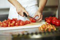 Tomaten werden auf einem Schneidbrett geschnitten. © mauritius images / foodcollection